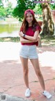 A woman in a red shirt and white shorts posing for a picture.