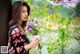 A woman holding a bunch of flowers next to a tree.