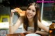 A woman sitting at a table eating a piece of bread.