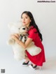 A woman in a red dress holding a white teddy bear.