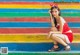 A woman in a red dress sitting on a colorful staircase.