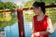 A woman in a red dress standing by a fence.