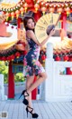 A woman in a floral dress holding a fan.