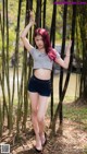 A woman with red hair standing in front of a bamboo forest.