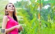 A woman in a pink tank top standing in a field.