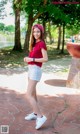 A woman in a red shirt and white shorts posing for a picture.