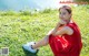 A woman in a red dress sitting on the grass.