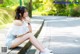 A woman sitting on the side of a road with her legs crossed.