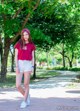 A young woman in a red shirt and white shorts posing for a picture.