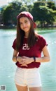 A woman in a red shirt and white shorts posing for a picture.