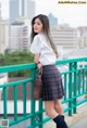 A woman in a school uniform standing on a bridge.