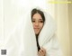 A woman wrapped up in a white blanket.