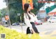 A woman in a white blouse and black skirt standing on the street.