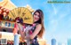 A woman in a cheongsam holding a yellow fan.