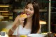 A woman sitting at a table eating a pastry.