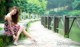 A woman in a red and black dress sitting on a stone walkway.