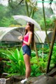 A woman standing in the rain holding an umbrella.