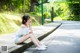 A woman sitting on the side of a road with her legs crossed.