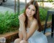 A woman in a white dress sitting on a brick wall.