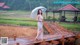 A woman standing on a wooden bridge holding an umbrella.