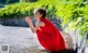 A woman in a red dress crouching down on the ground.