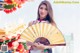 A woman in a chinese dress holding a fan.