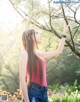 A woman standing next to a tree in a park.