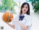 A woman in a school uniform holding a basketball.