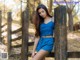 A woman leaning against a wooden fence in the woods.