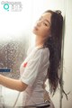 A woman in a white shirt is standing in a shower.