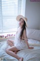 A woman sitting on a bed wearing a straw hat.