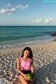 A woman sitting on a beach holding a green ball.