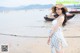 A woman in a straw hat is standing on the beach.