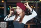 A woman in a beret holding a glass of iced coffee.