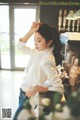 A woman in a white blouse and jeans standing in front of a counter.