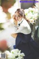 A woman sitting on the ground next to a bunch of flowers.