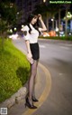 A woman in a police uniform is standing on the side of the road.