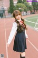 A woman in a school uniform standing on a track.