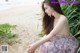 A woman sitting on a sandy beach next to the ocean.