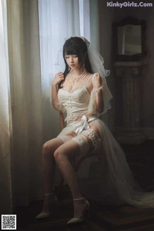 A woman in a wedding dress sitting on a chair.
