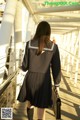 A woman in a school uniform is walking on a bridge.