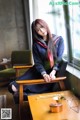 A woman in a school uniform sitting on a chair.