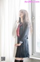 A woman in a school uniform leaning against a window.