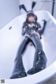 A woman in a black latex outfit laying in a bathtub.