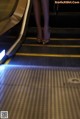 A woman is walking down an escalator with her legs up.