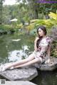 A woman sitting on a rock by a pond.