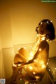 A naked woman sitting on top of a stool covered in lights.