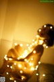 A woman sitting on top of a bed covered in lights.