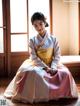 A woman in a traditional korean dress sitting on the floor.