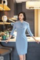 A woman in a blue dress standing in a kitchen.